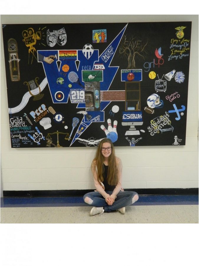 Senior Allison Weissman with her mural, jam packed with school spirit.  “Despite group identities being essential to who we are, it is important that we never lose sight that we are a part of the same team here at Warren Hills.”  (Photo by Katie Winch) 
