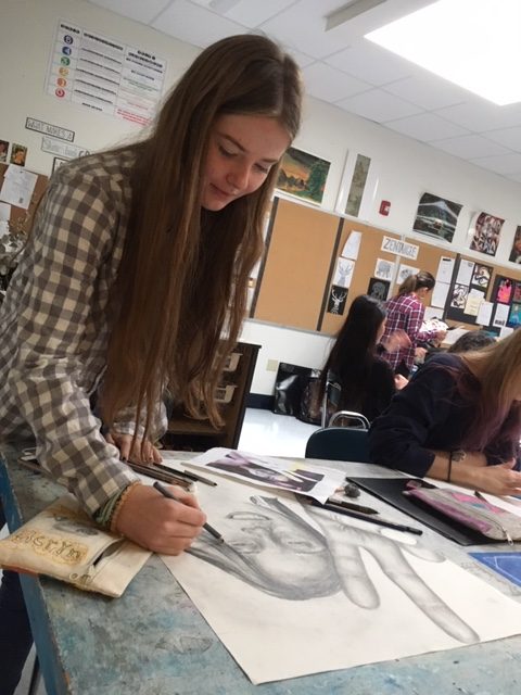 Art teacher Vittoria Signeona had her Intermediate Arts students draw their self-portraits this fall for their portfolios.  Drawing themselves is a long process that takes a few weeks to complete. Just as with most anything they draw, they use grid lines so everything is proportional. Senior Meryn McFarland said it takes a good amount of concentration to draw. “You need to focus without any distractions,” she said. “It helps to have music.” The self-portraits will be posted in the art wing right before winter break. (Photo by Sofia Senesie)