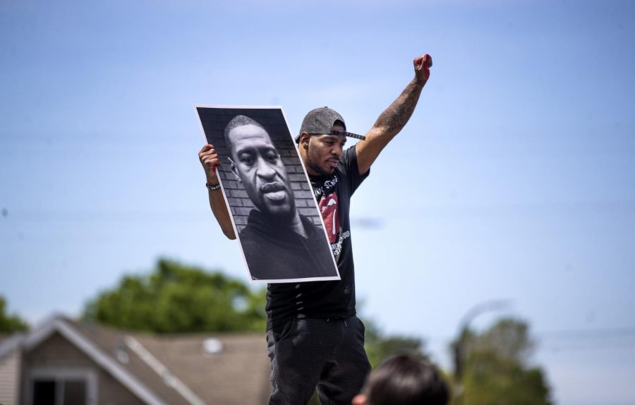 Tony L. Clark holds a photo of George Floyd outside of the Cup Foods store where he was killed while in police custody during a third day of demonstrations in Minneapolis on Thursday, May 28, 2020. (Jerry Holt/Minneapolis Star Tribune/TNS)

