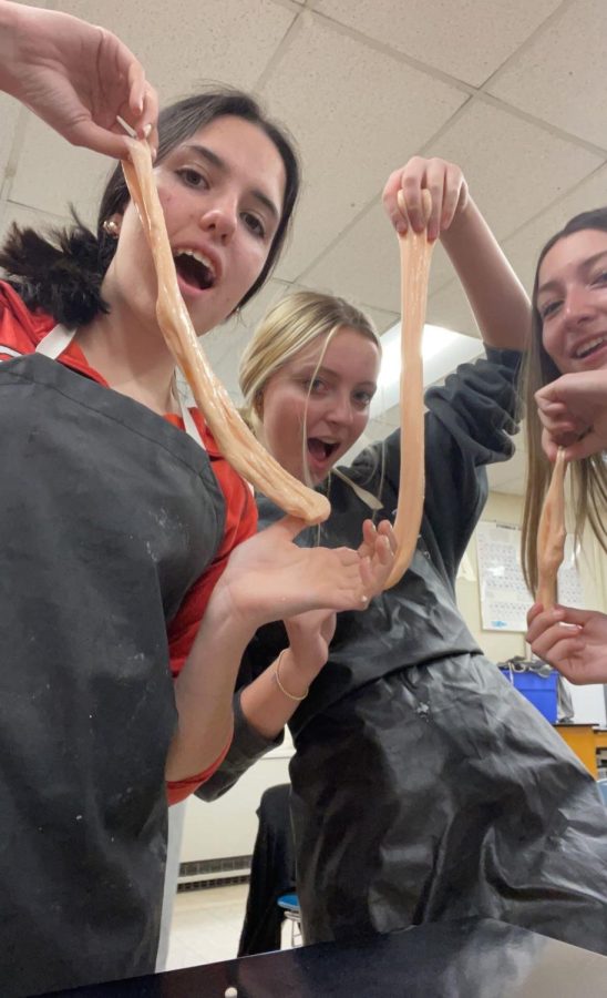 Students Bogdana Viznovych, Peyton Bigelow and Natasha Waslik, all sophomores, enjoy some slime time in a recent Honors Chemistry class taught by Science Teacher Elizabeth Nicolosi. Students created slime throughout the week in order to discover physical and chemical changes. Glue, water and Borax were used, and even food dye, so that the students could choose what color their solution would be. The sophomores said they had a blast mixing the ingredients and playing with the finished product afterwards. They took notes on substance changes for a full learning experience during the lab. “It was a really nice opportunity to learn about chemistry but have fun at the same time,” Bigelow said. Nicolosi said that the annual experiment went well and everyone loved it.  (Photo courtesy of Peyton Bigelow)