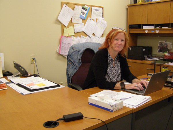 Susan Rader working at her desk, answering students’ questions and concerns. She has been a fixture in
the main office since she took the position in 2011. (Photo by Shelia Bazelais)